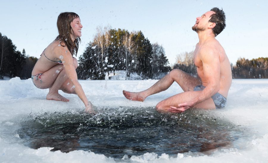 Man en vrouw bij een gat in het ijs in onderkleding